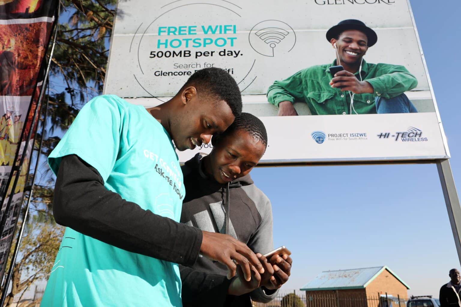 Commuters using their phones under an OMNi-Fi billboard